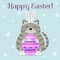 A gray cat in the ears and slippers of a rabbit sits and holds a purple Easter egg. Happy Easter.