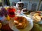 Gray cat with is sitting at the table with cakes on it. Mug with tea.Cookies and pretzel