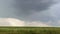 Gray clouds and pouring rain in green field