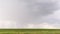 Gray clouds and pouring rain in green field