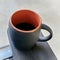 A gray coffee mug on the arm of an outdoor patio chair