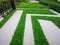 Gray color tiles floor on strip line concrete pavement and green  grass carpet lawn in a garden