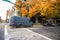 Gray commercial cargo mini van for small business and local deliveries parking on the city street crossroad with autumn trees