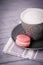 Gray cup of coffee latte and pink strawberry macaroon on a gray background