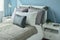 Gray, dark gray and beige pillows on bed with blue wall