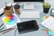 The gray desk with laptop, notepad with blank sheet, pot of flower, stylus and tablet for retouching