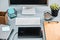 The gray desk with laptop, notepad with blank sheet, pot of flower, stylus and tablet for retouching