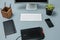 The gray desk with laptop, notepad with blank sheet, pot of flower, stylus and tablet for retouching