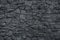 Gray dirty stone wall. Texture of grey granite. Dark rough rocks background. Weathered dark gray grunge building`s facade. Stone s