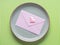 Gray dish with pink envelope on green