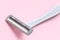 Gray disposable plastic razor blade close up on pink backround, removing unwanted hair for women