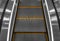 Gray escalator steps with orange lines close-up.