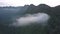 Gray fog and little clouds hang among high mountain range