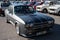 Gray Ford Capri racing car with two black stripes and a hood lock parked outside