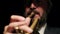 Gray-haired, bearded musician plays musical trumpet in studio on black background, closeup of mouth blowing into