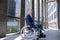 Gray haired disabled man wearing official style suit in wheelchair city background.
