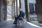 Gray haired disabled man wearing official style suit in wheelchair city background.