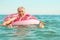 Gray-haired funny man swims on inflatable circle in the sea