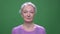 Gray haired grandmother shaking head being annoyed to disagree isolated on green chromakey background.