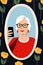 Gray-haired granny, familiar with modern technology, taking a selfie in a mirror