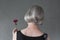Gray-haired lady holding red dahlia