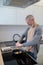 A gray-haired man cooking omlette in the kitchen