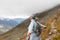 The gray-haired woman spread her arms, as if in flight, standing in the mountains on a rocky path. Austria, Alps