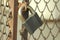 Gray iron shiny padlock hanging on an iron door in the street