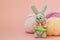 Gray knitted hare stands on the background of multi-colored balls of yarn on a pink background. There is a place for text
