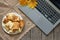 Gray laptop lies on a brown lace napkin and next to a plate of pancakes on a wooden table, a laptop on the table