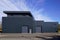 Gray large industrial building exterior warehouse grey hangar exterior with rolling gates in blue sky