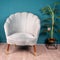 Gray living room chair with a soft shell design and a plant before the blue wall