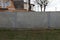 Gray long concrete fence outside in green grass