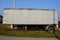 Gray long metal trailer  on wheels in the grass on the street