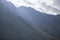 A gray low cloud on a high peak. High black rock in low clouds. Surreal gloomy mountains