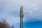 Gray metal cell tower carrying antennas of cellular networks on the blue sky with white clouds background in sunny day