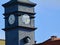 Gray metal covered clock tower. white clock face. golden clock hands