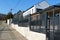 Gray metal fence with white house. street scene in diminishing perspective