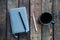 Gray notepad on the table. Next to a cup of coffee and a pen. On wooden