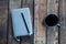 Gray notepad on the table. Next to a cup of coffee and a pen. On wooden