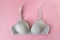 Gray organic or recycled cotton bra on pastel pink background, top view, copy space, flat lay. Concept of femininity, comfort,