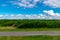 Gray path near a green field under a bright blue sky