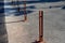 Gray pillars separating the park path from the road. deliberately rusty steel bollards bent into a double space slot connected by