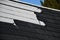The gray plastic shingles on the roof of the house visually look like those made of wood. however, plastic is cheaper and durabili