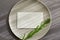 Gray plate with a white invitation card on a gray background closeup