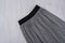 Gray pleated skirt on wooden background. Fashionable concept. Cl