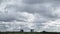 Gray rainy clouds run in sky over apartment houses and woods