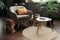 A gray reading chair with a yellow cushion by the window and many books next to it in a room with houseplants