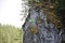 A gray rock covered with moss, grass, and trees. It has a green sign in Russian `holey stone 25km`. Olenyi Ruchy is a natural park