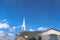 Gray roof and white steeple of church on winter view of snowy Wasatch Mountains